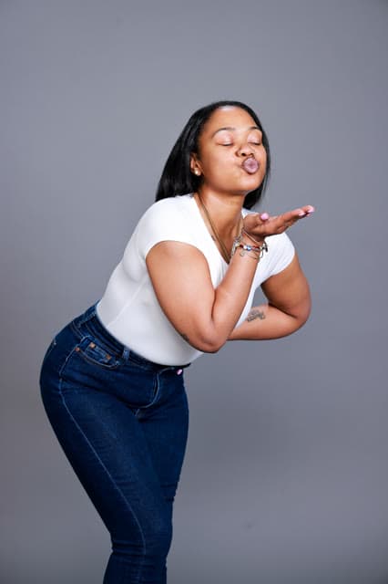 Studio portrait, mid-laugh, blowing a kiss to the camera.