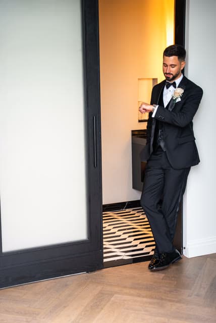 Groom checking the time in the hallway before walking out.