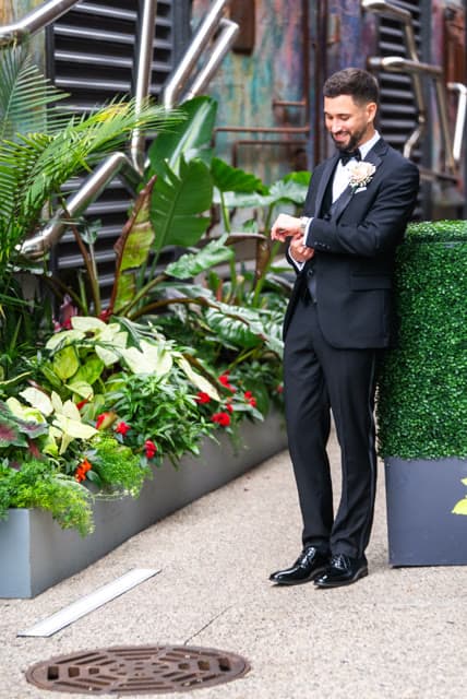 Groom adjusting his cufflinks in the same courtyard.