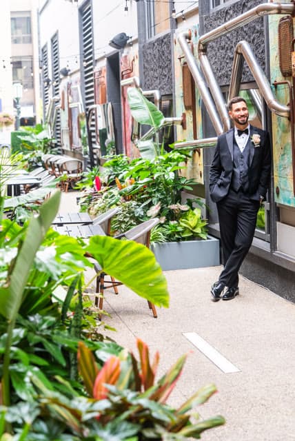 Groom, candid smile, stepping out into the courtyard.