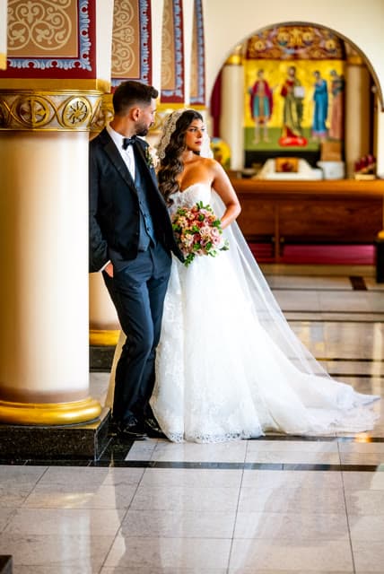 Bride and groom portrait beside a gold column inside the church.