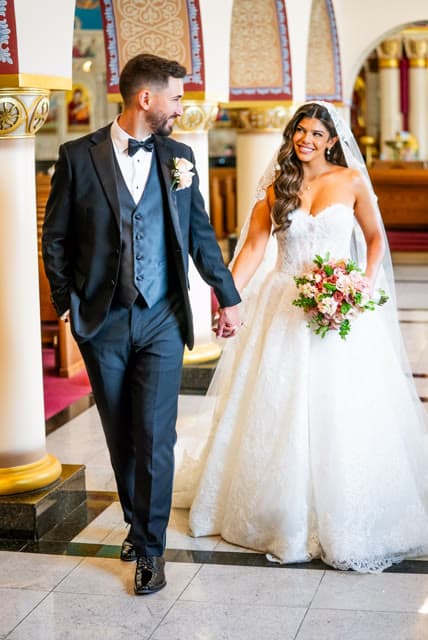 Bride and groom walking hand in hand through the church.