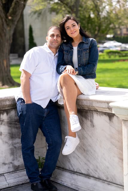 Engagement session, seated together on a stone wall.