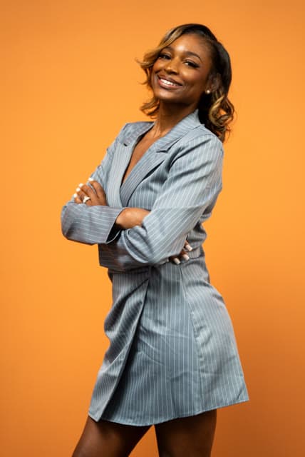 Branding portrait, arms crossed against an orange backdrop.