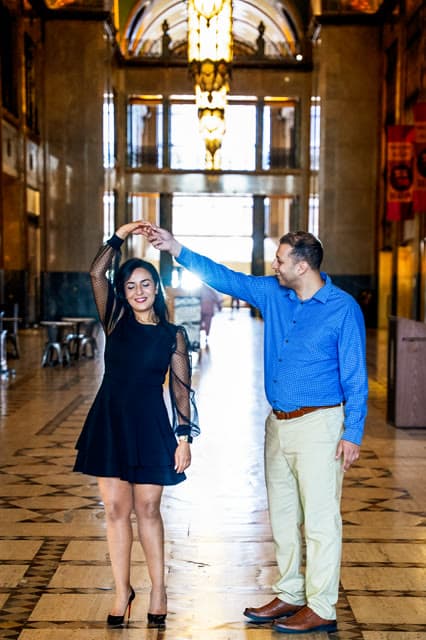 Couple dancing in a grand, sunlit hallway.