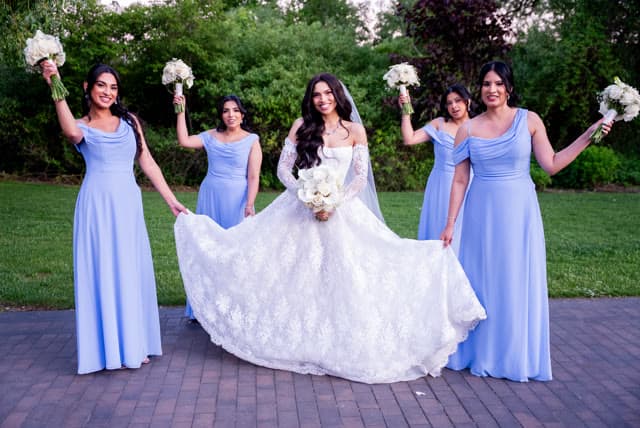 Bride with her bridesmaids, bouquets raised.