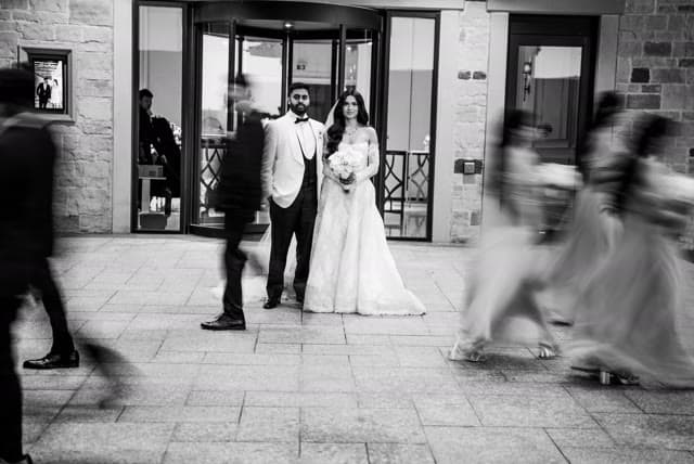 Candid, black and white — guests in motion around the couple.